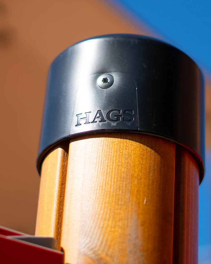 Close up of HAGS wooden pole with rubber cap for playground units. It has the HAGS logo on it.
